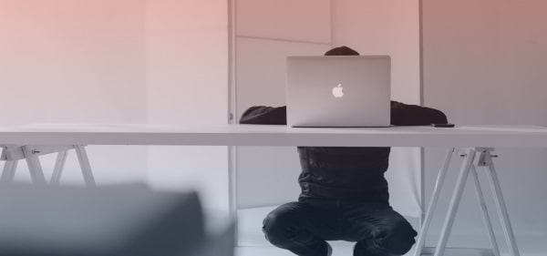 man in an empty room working on his laptop without using a chair